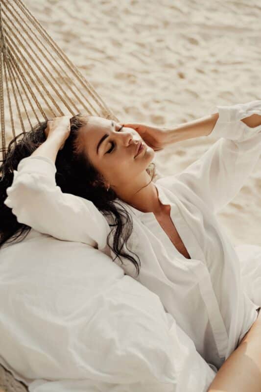 Model-laying-on-hammock-on-beach